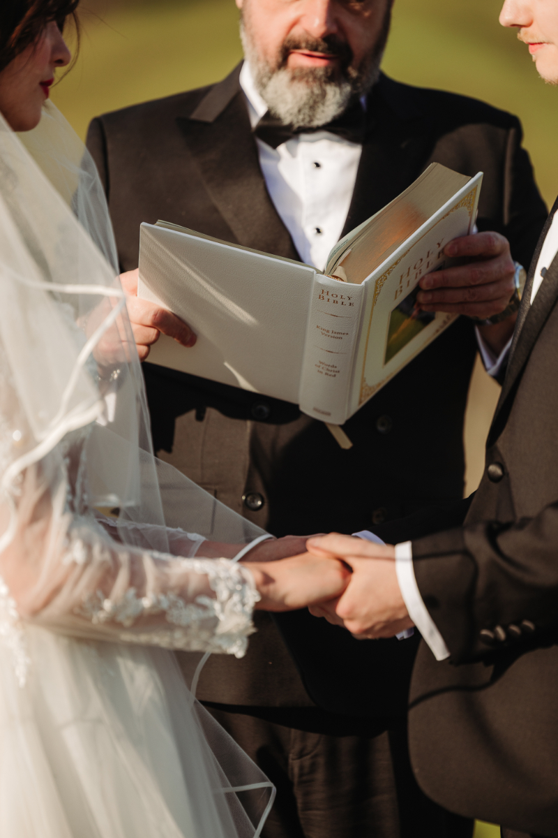 Couple holds hands during ceremony, capturing a simple adventure elopement package moment with heartfelt vows