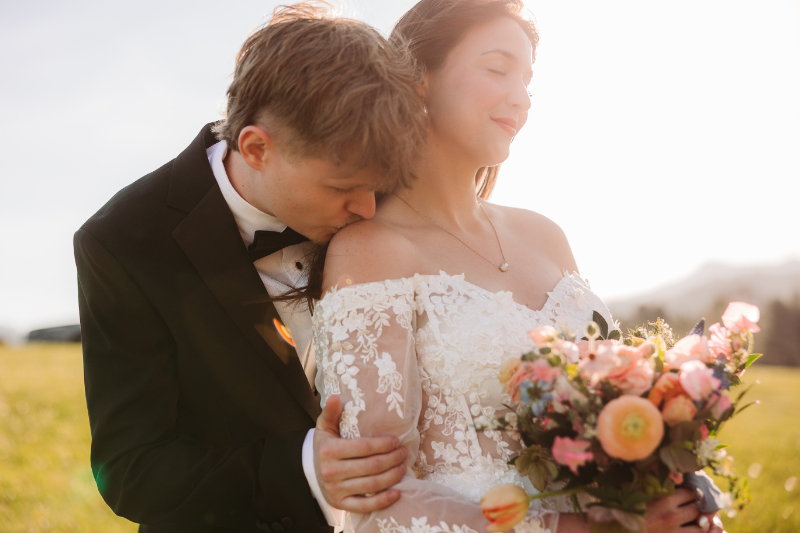 Groom embraces bride with bouquet, capturing a romantic moment from their adventure elopement package experience