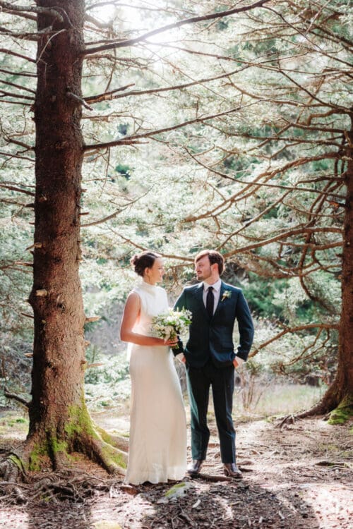 Bride and groom standing together in the forest during an intimate Asheville elopement vs wedding celebration.