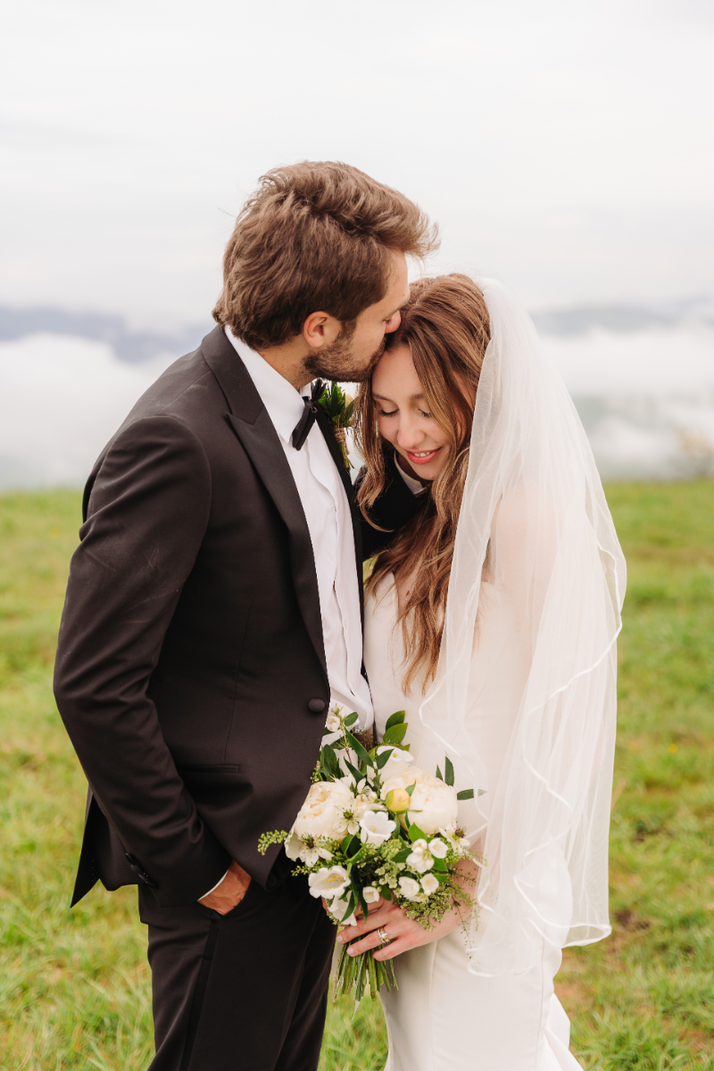 Bride and groom embracing during an intimate mountain elopement with soft light and scenic outdoor views.