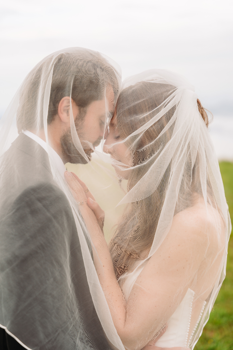 Bride and groom sharing an intimate moment beneath a veil during a mountain elopement ceremony outdoors.