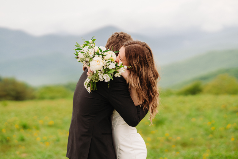 Couple hugging during a remote elopement in the Blue Ridge Mountains with scenic mountain views behind them.