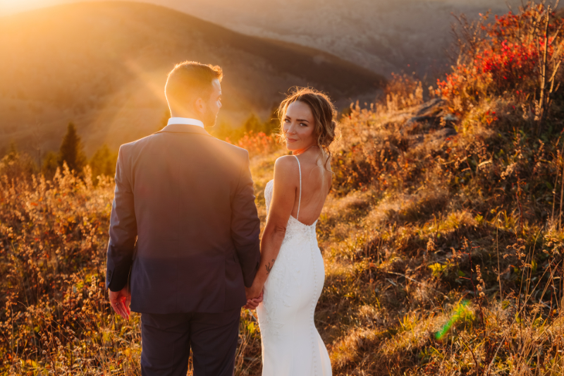Couple holding hands in golden mountain light during sunrise vs sunset elopement in Blue Ridge Mountains