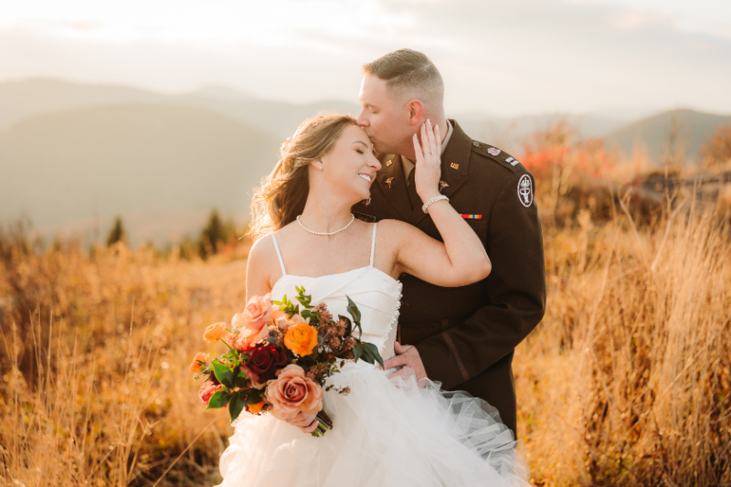 Couple embracing during a fall elopement surrounded by Blue Ridge Mountains fall colors and golden fields.