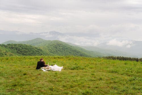 Newly married couple enjoying a picnic after their Hot Springs NC elopement overlooking the Blue Ridge Mountains at Max Patch.