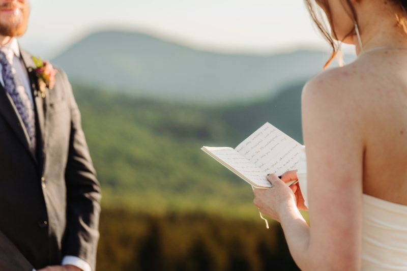 Bride reading personal vows during an elopement in North Carolina overlooking the Blue Ridge Mountains.