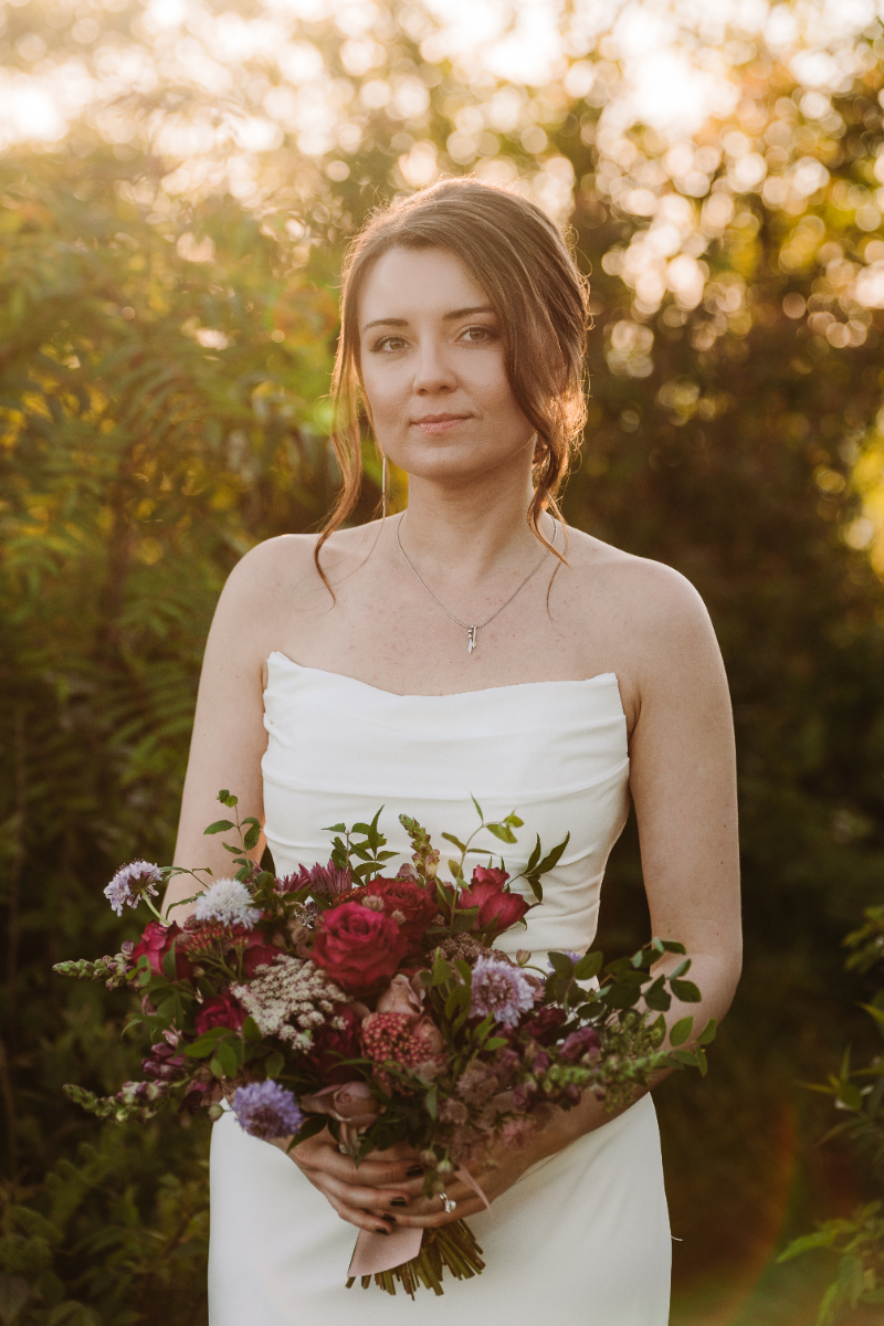 Bride holding a colorful bouquet during an elopement in North Carolina at golden hour.