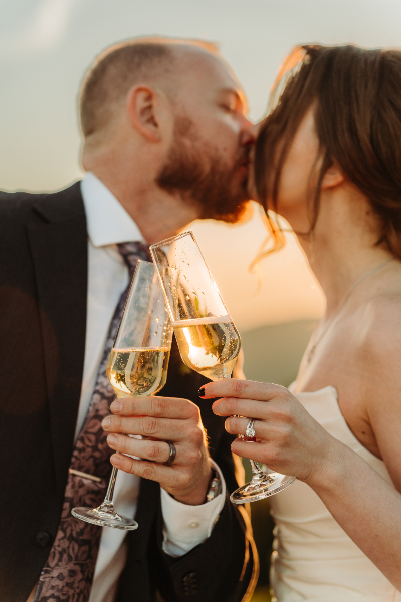 Couple celebrating their elopement in North Carolina with a champagne toast at sunset.