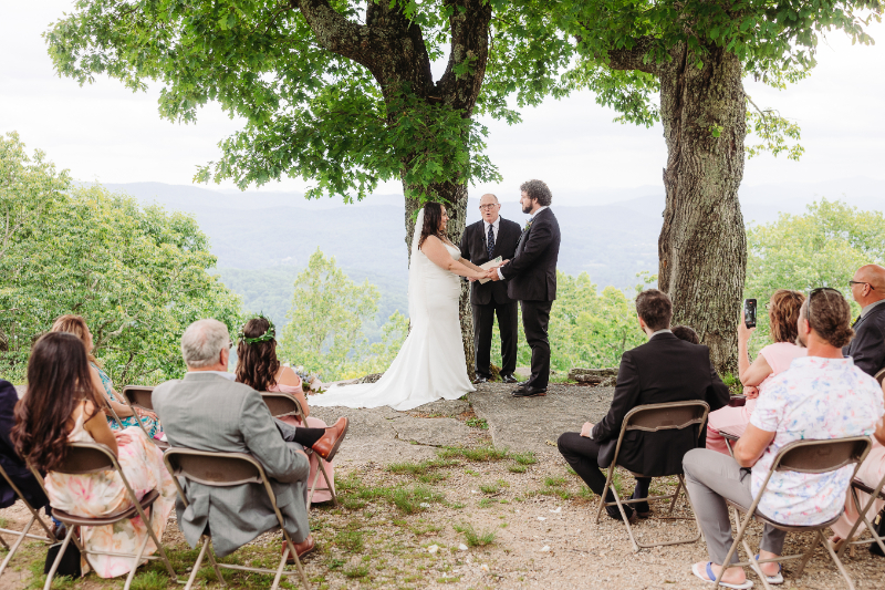 Elopement with family ceremony in the Blue Ridge Mountains with guests gathered beneath trees.