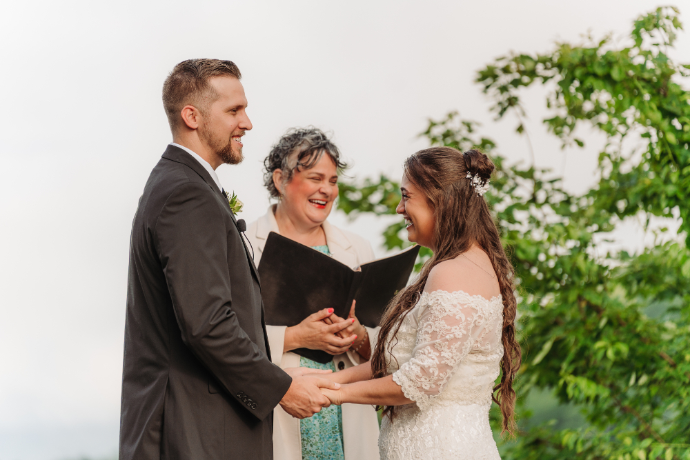 Couple exchanging vows during an anniversary vow renewal ceremony with an officiant in the Blue Ridge Mountains.