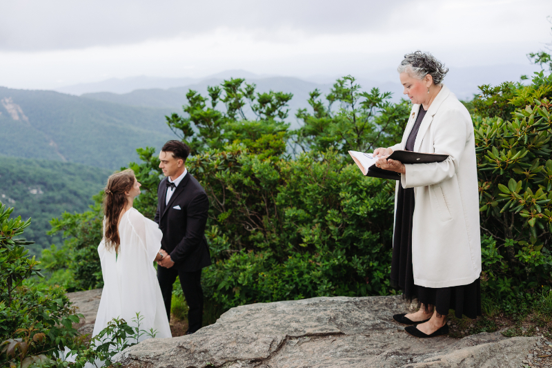 Officiant leading a destination elopement ceremony with a couple overlooking the Blue Ridge Mountains in Asheville.