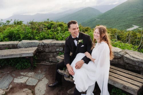 Newly married couple smiling after their destination elopement at a scenic Blue Ridge Mountain overlook.