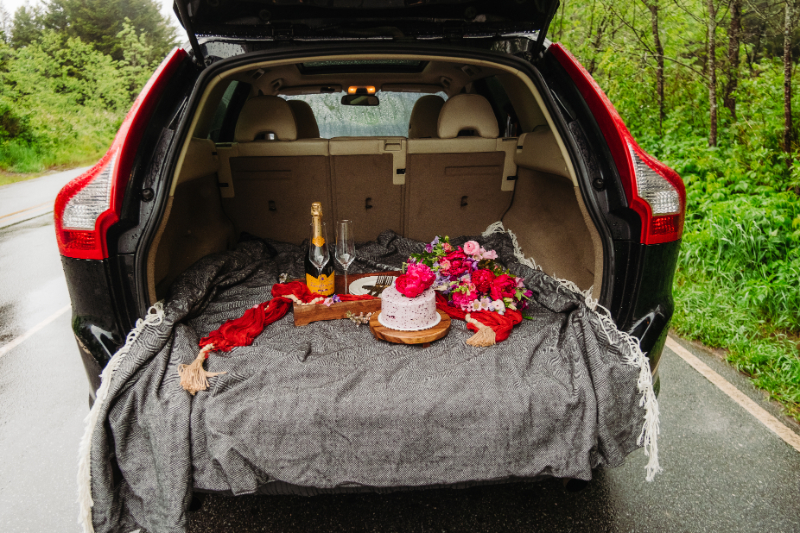 Picnic setup with cake and champagne in the back of an SUV after a mountain elopement ceremony.