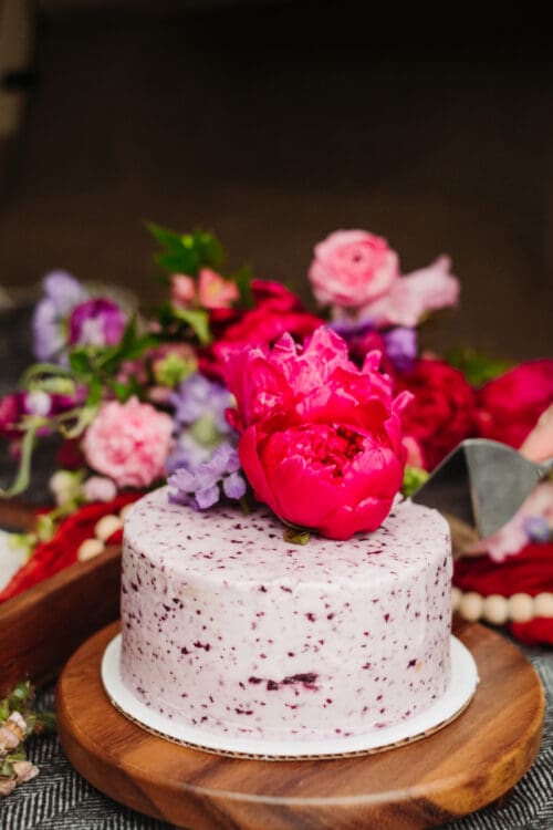 Small berry cake topped with bright pink flowers during an intimate mountain elopement celebration.