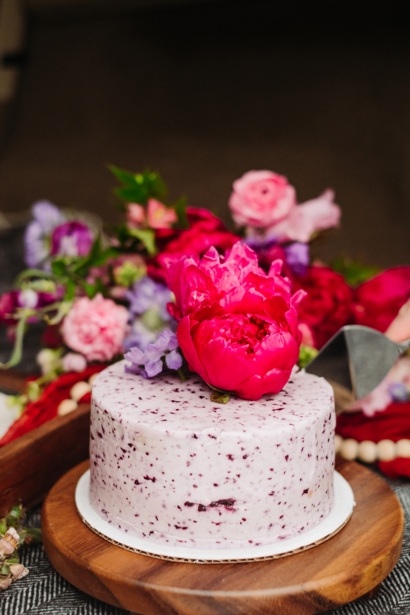 Small berry cake topped with bright pink flowers during an intimate mountain elopement celebration.
