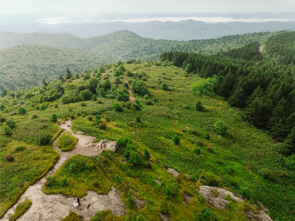 Aerial view of couple on a rocky mountain overlook during an elopement with an Asheville wedding planner.