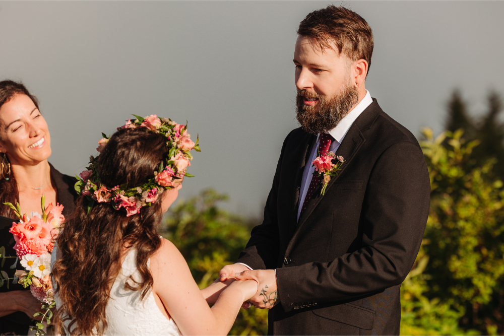 Bride and groom hold hands during an intimate mountain wedding ceremony.