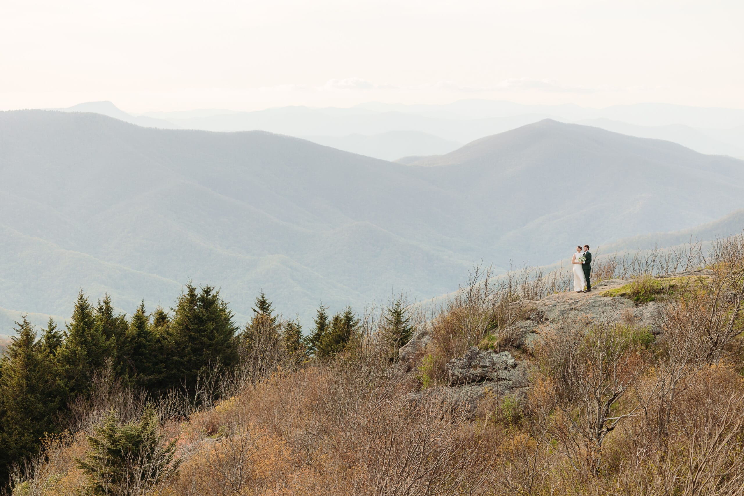 Newlyweds overlooking layers of the Blue Ridge Mountains during their intimate elopement