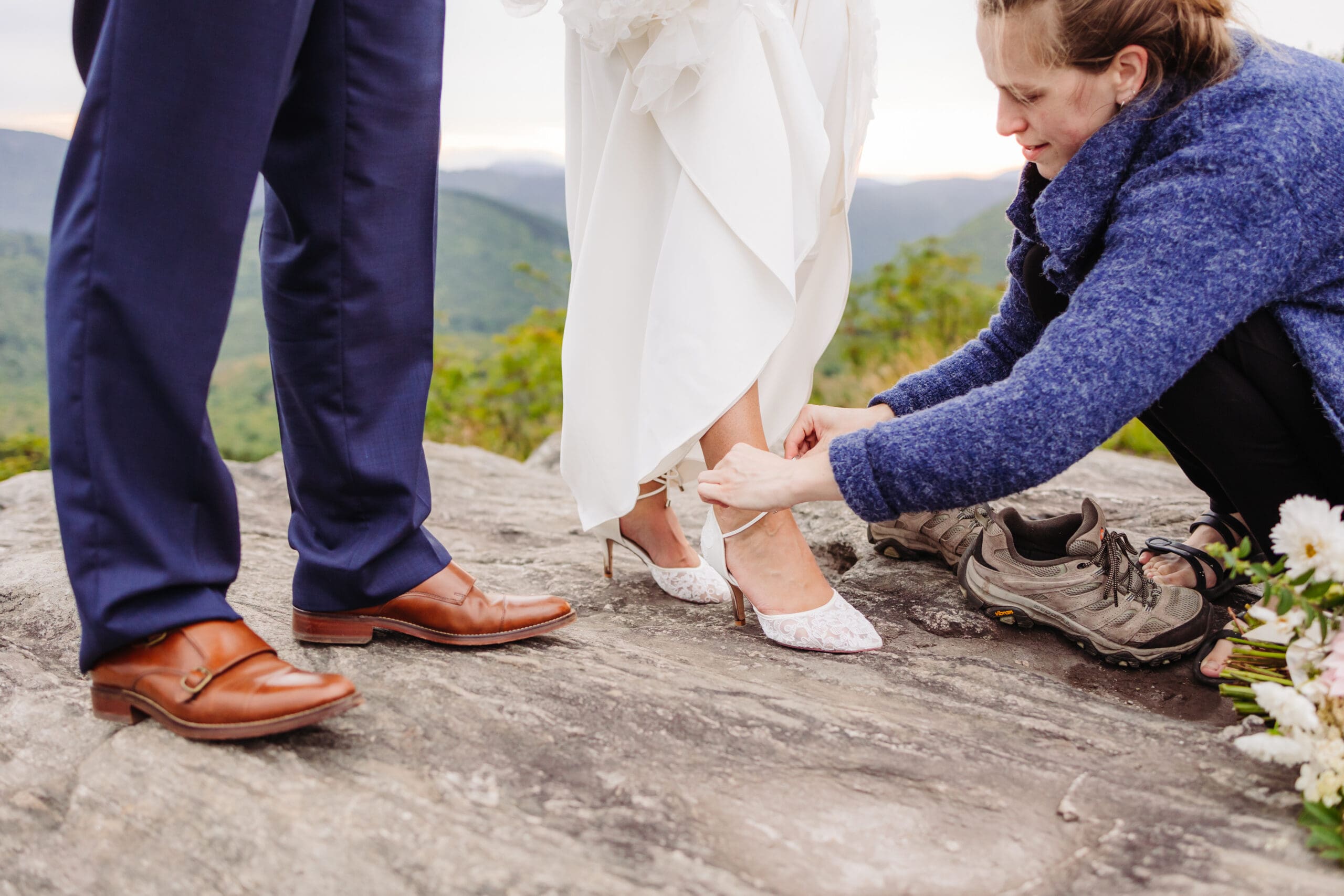 Elope Outdoors assistant helping a bride with her shoes at a mountain elopement