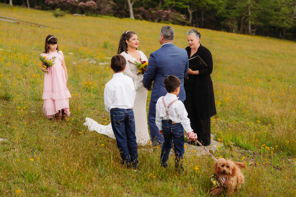 Couple holding their outdoor ceremony with children nearby while hiking with kids in the mountains.