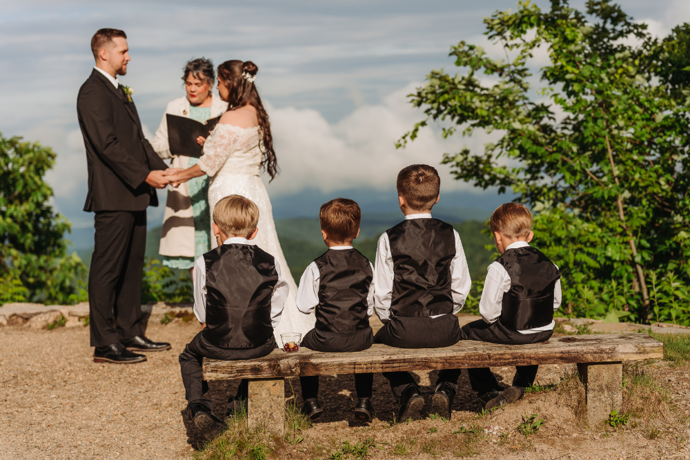 Children watching a couple exchange vows during an intimate outdoor mountain elopement ceremony.