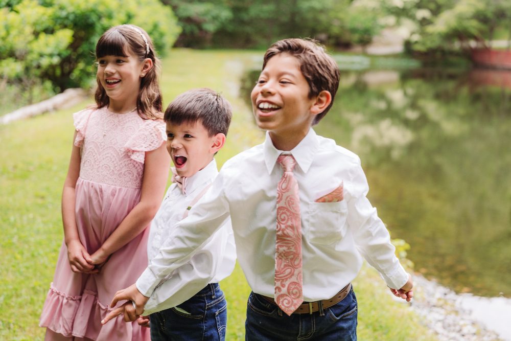 Three children laughing together outdoors during a joyful family elopement celebration in the mountains.