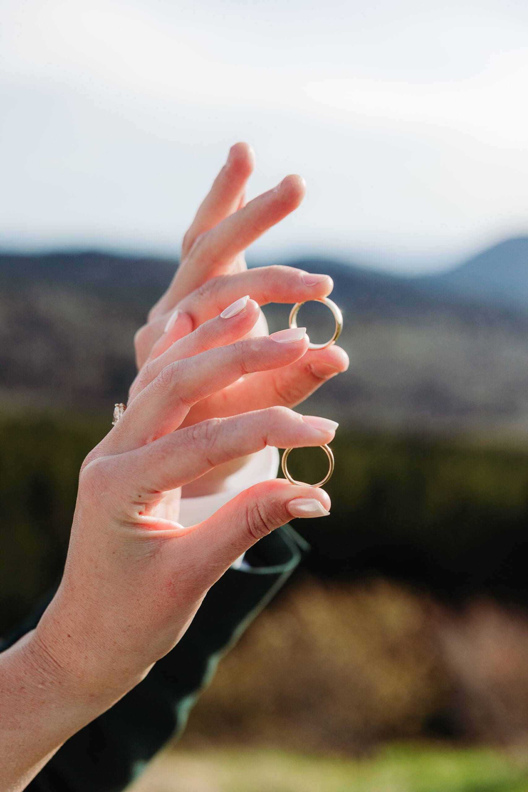 Couple holding their wedding rings with the Blue Ridge Mountains in the background