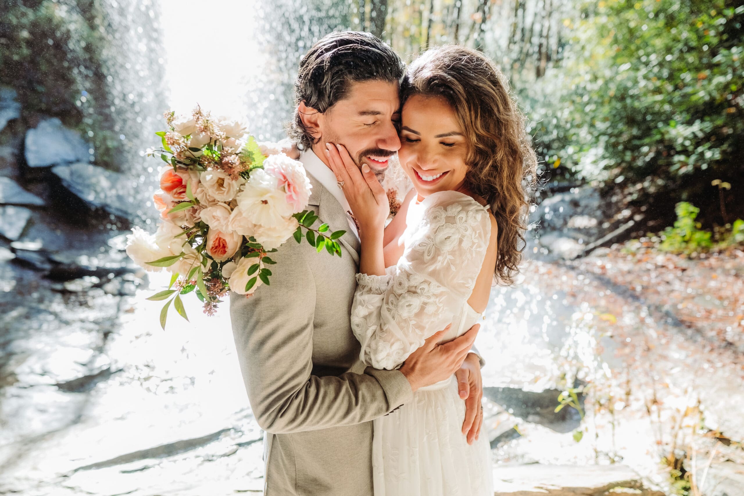 Bride and groom embracing in front of a waterfall during their intimate North Carolina elopement