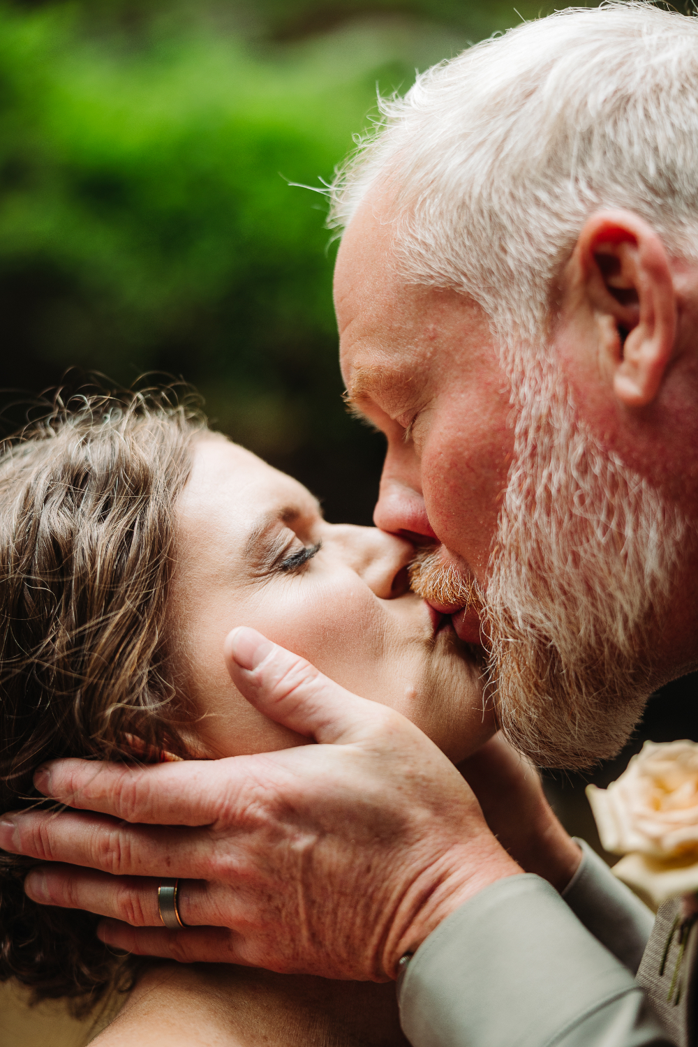 Newlywed couple sharing a sweet kiss during their romantic outdoor wedding over 40.