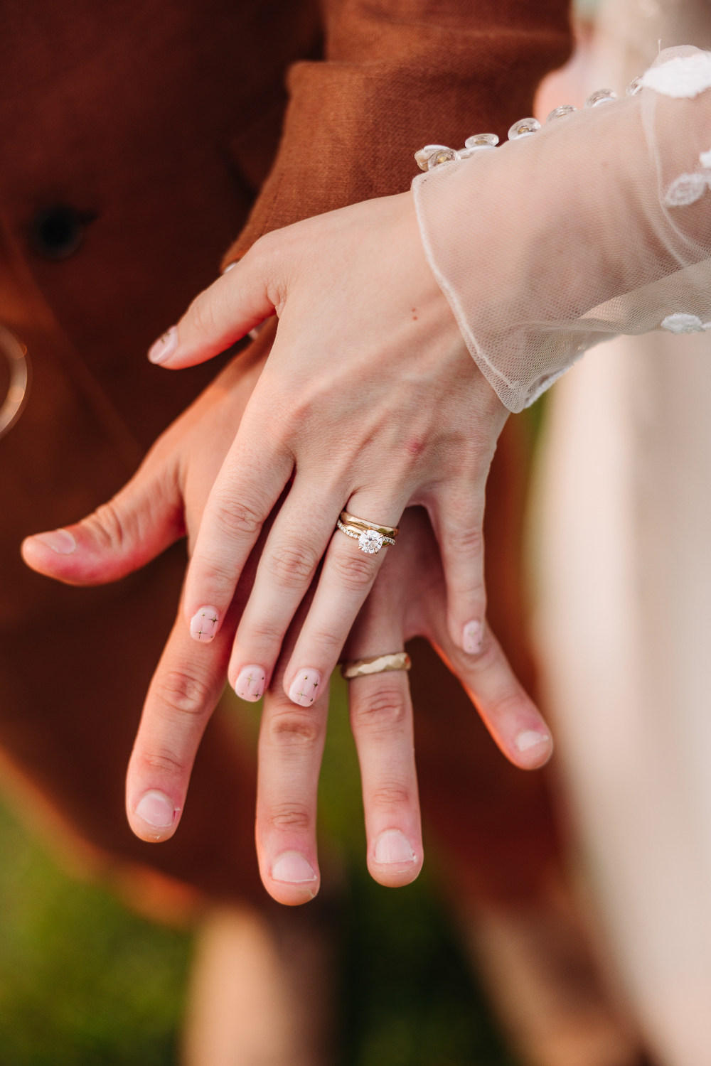 Bride and groom showing their wedding bands while holding hands after their ceremony.