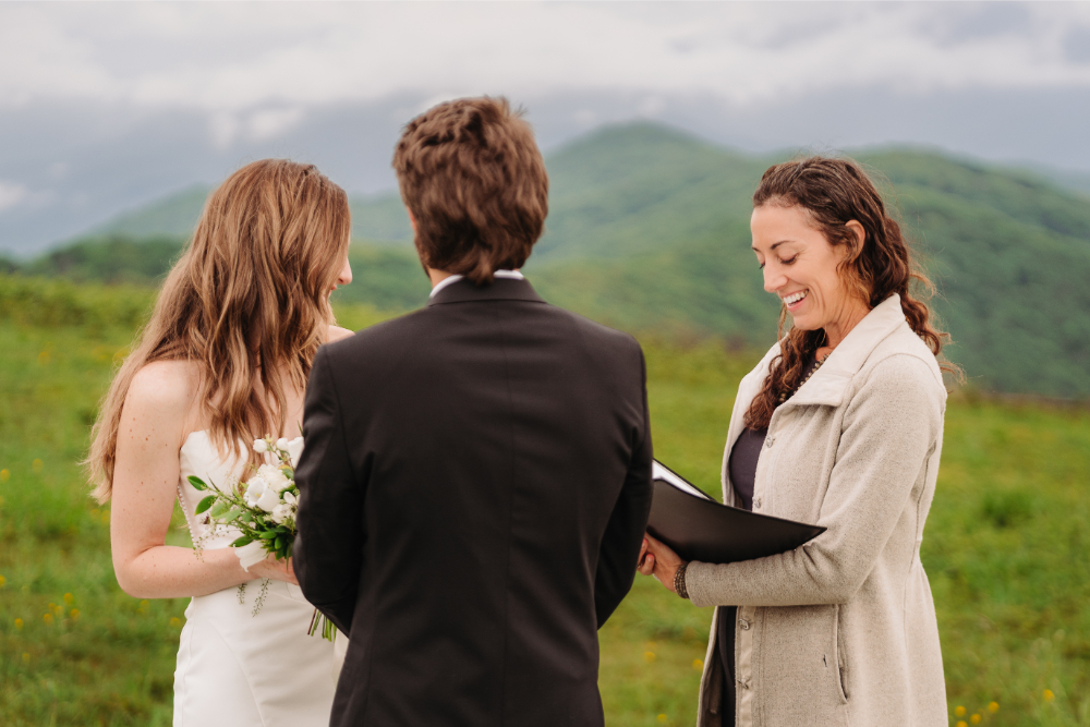 Asheville wedding officiant celebrates with a couple during their joyful ceremony filled with flowers and laughter.