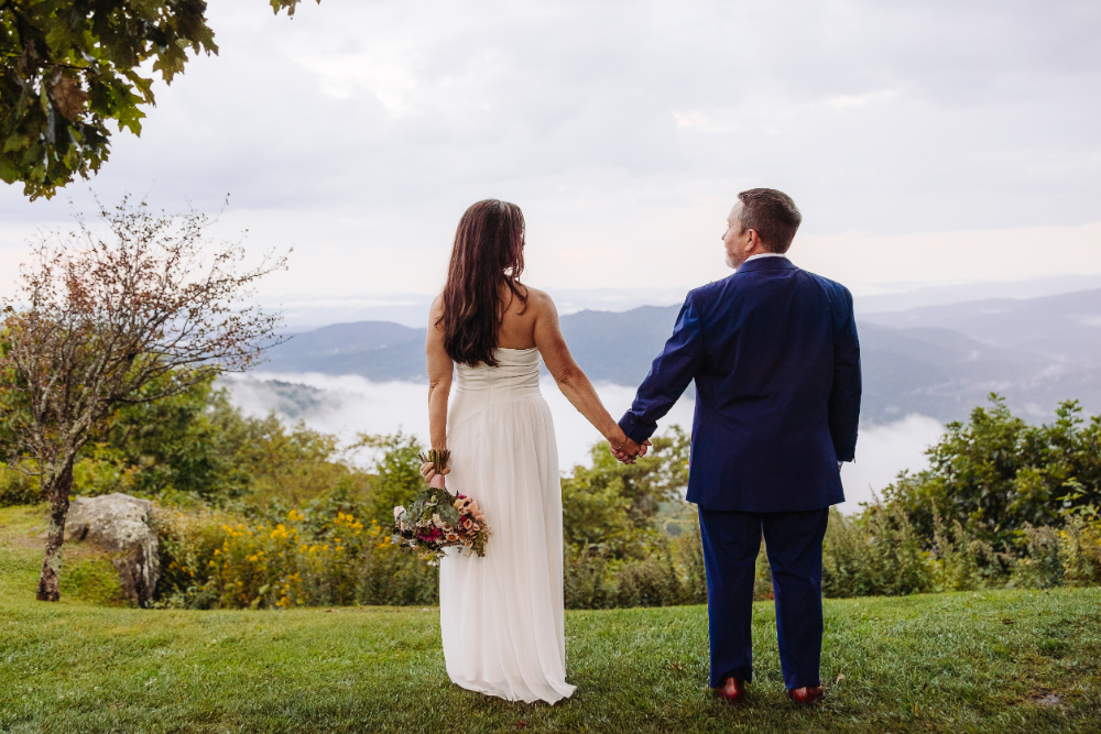 Bride and groom holding hands while overlooking misty Blue Ridge Mountains, inspiring scenic intimate wedding ideas.