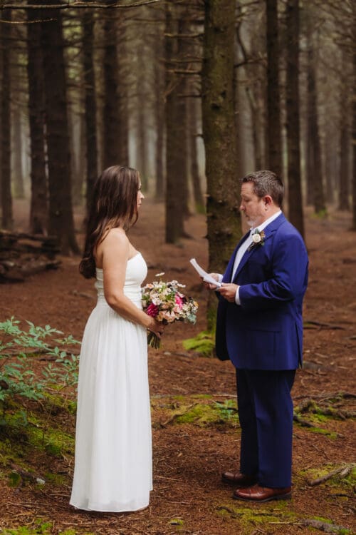 Groom reading his vows to the bride during a peaceful forest ceremony, inspiring intimate wedding ideas.